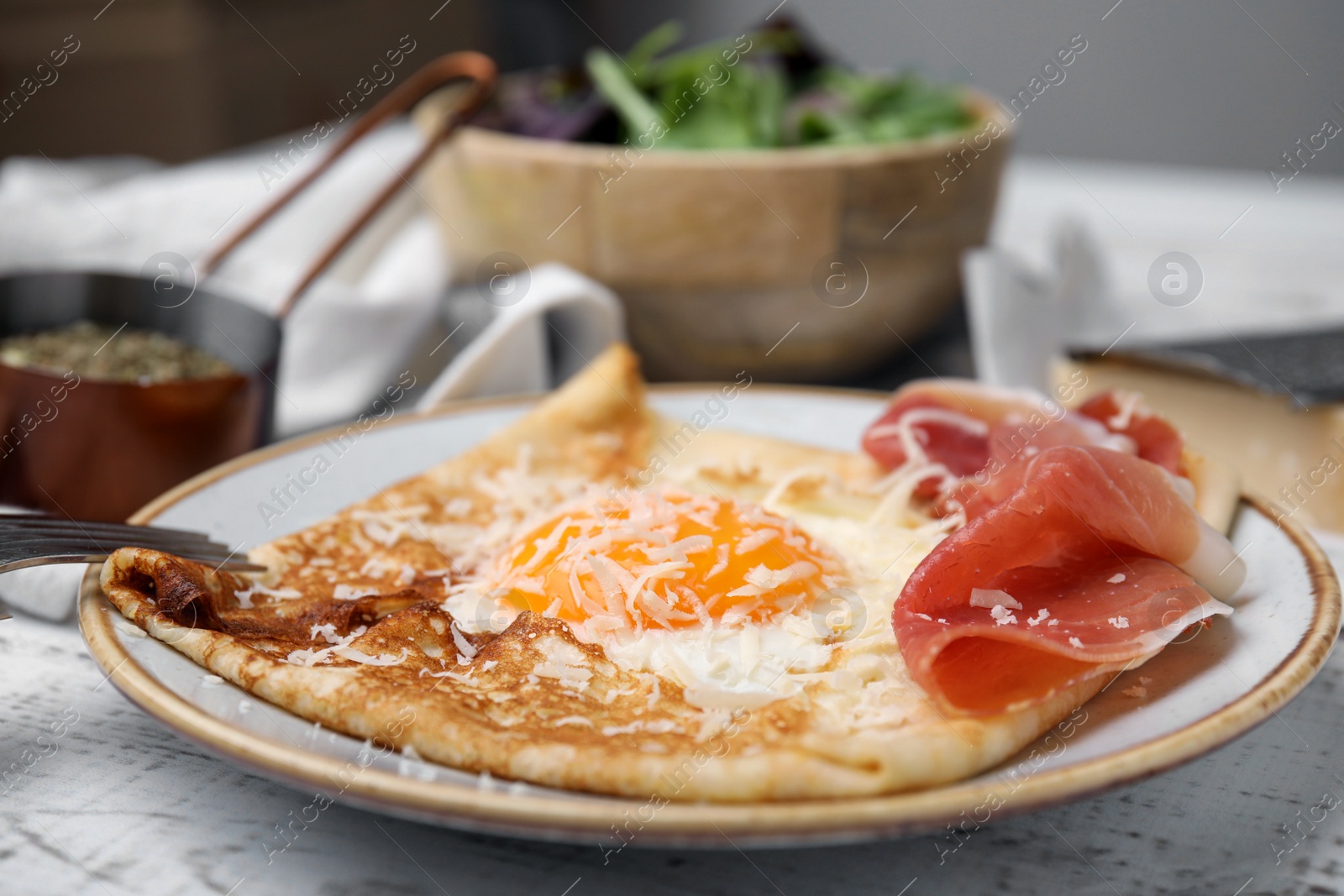 Photo of Delicious crepe with egg served on white wooden table, closeup. Breton galette