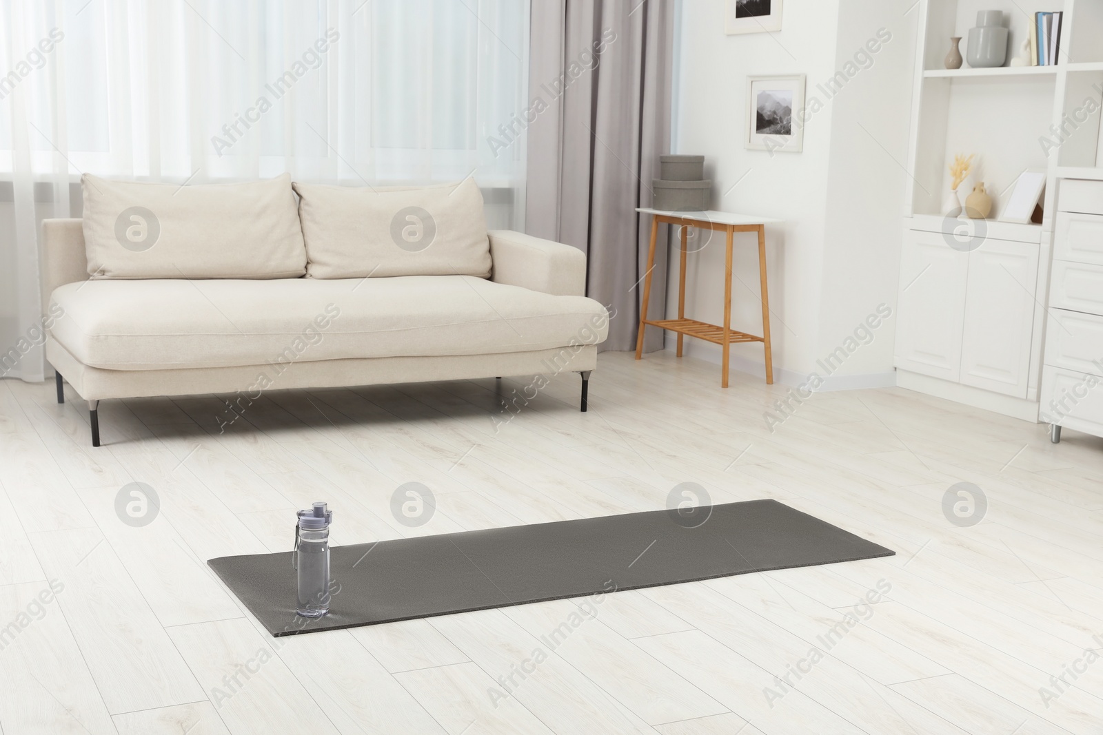 Photo of Yoga mat and bottle of water on floor in room