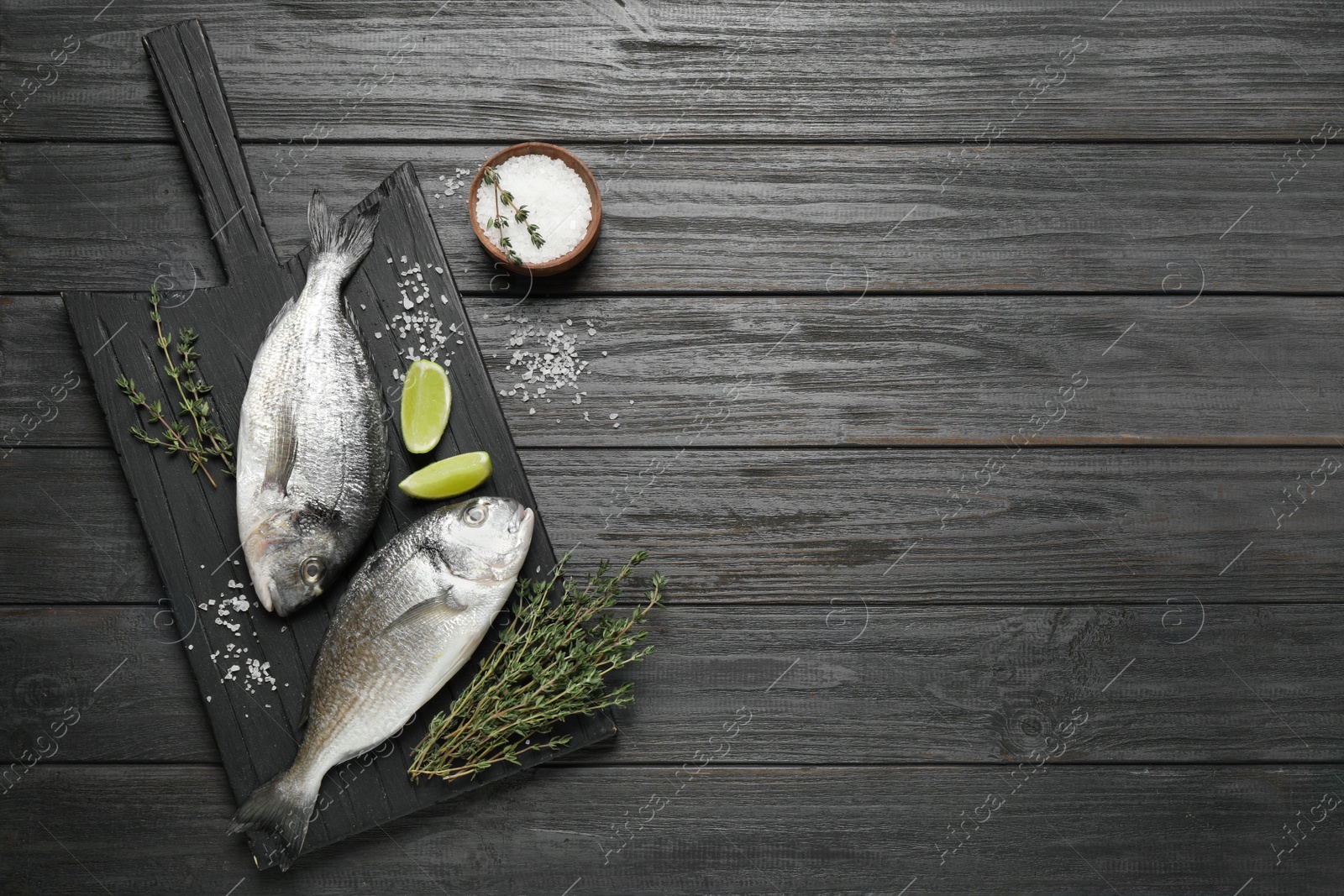 Photo of Raw dorada fish on black wooden table, flat lay. Space for text