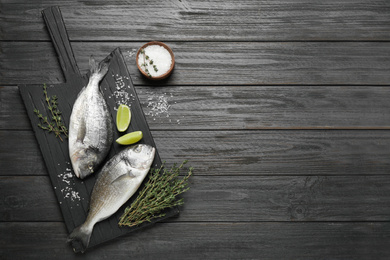 Photo of Raw dorada fish on black wooden table, flat lay. Space for text