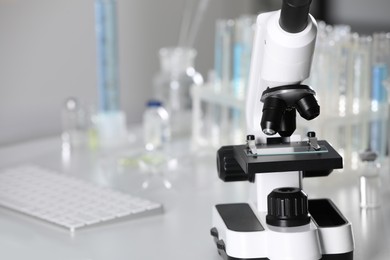 Photo of Modern medical microscope on white table in laboratory, closeup. Space for text