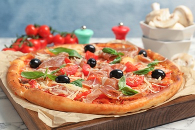 Delicious pizza with tomatoes and meat on table, closeup