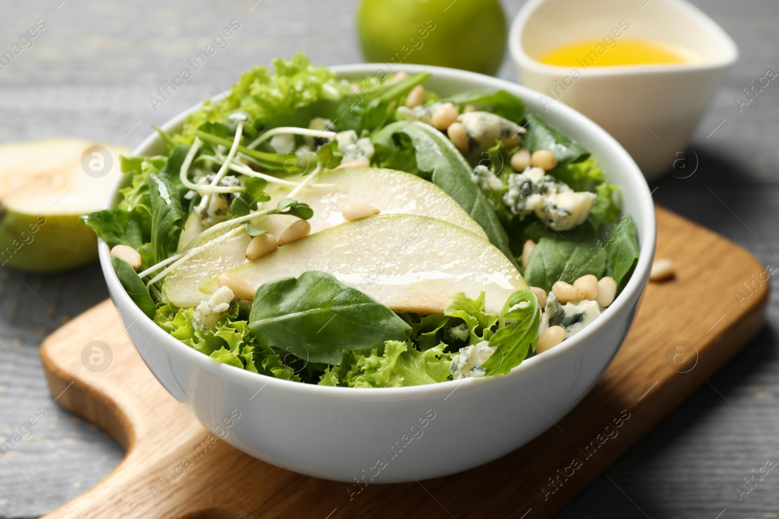 Photo of Fresh salad with pear on grey wooden table, closeup