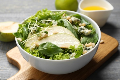 Fresh salad with pear on grey wooden table, closeup