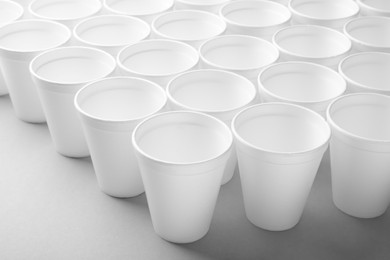 Many styrofoam cups on light grey background, closeup