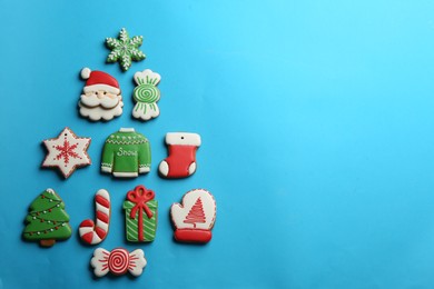 Delicious gingerbread cookies arranged in shape of Christmas tree on light blue background, flat lay. Space for text