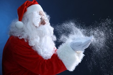 Photo of Merry Christmas. Santa Claus blowing snow on dark blue background