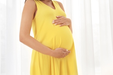 Beautiful pregnant woman near window at home