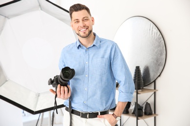 Photo of Professional photographer with camera and lighting equipment in studio