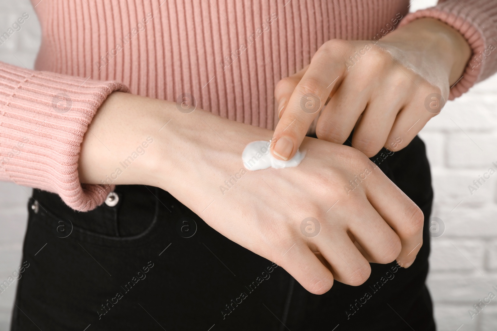 Photo of Woman applying ointment on her hand indoors, closeup