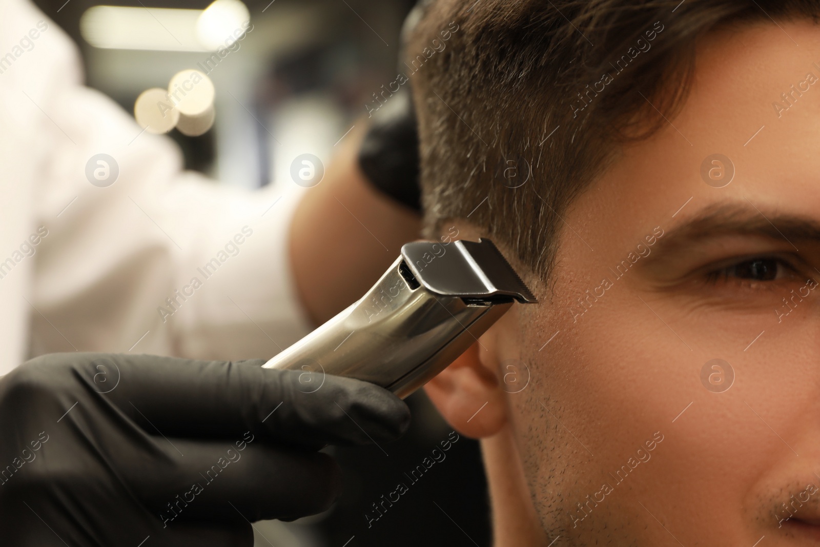 Photo of Professional hairdresser making stylish haircut in salon, closeup