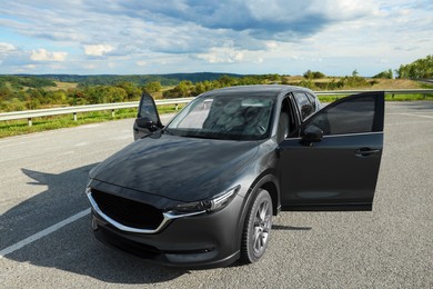 Photo of New black modern car with open doors on asphalt road