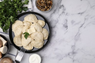 Delicious dumplings (varenyky) with mushrooms, parsley, butter and sour cream served on white marble table, flat lay. Space for text