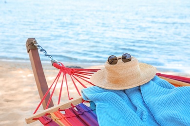 Colorful hammock with blanket, straw hat and sunglasses at seaside