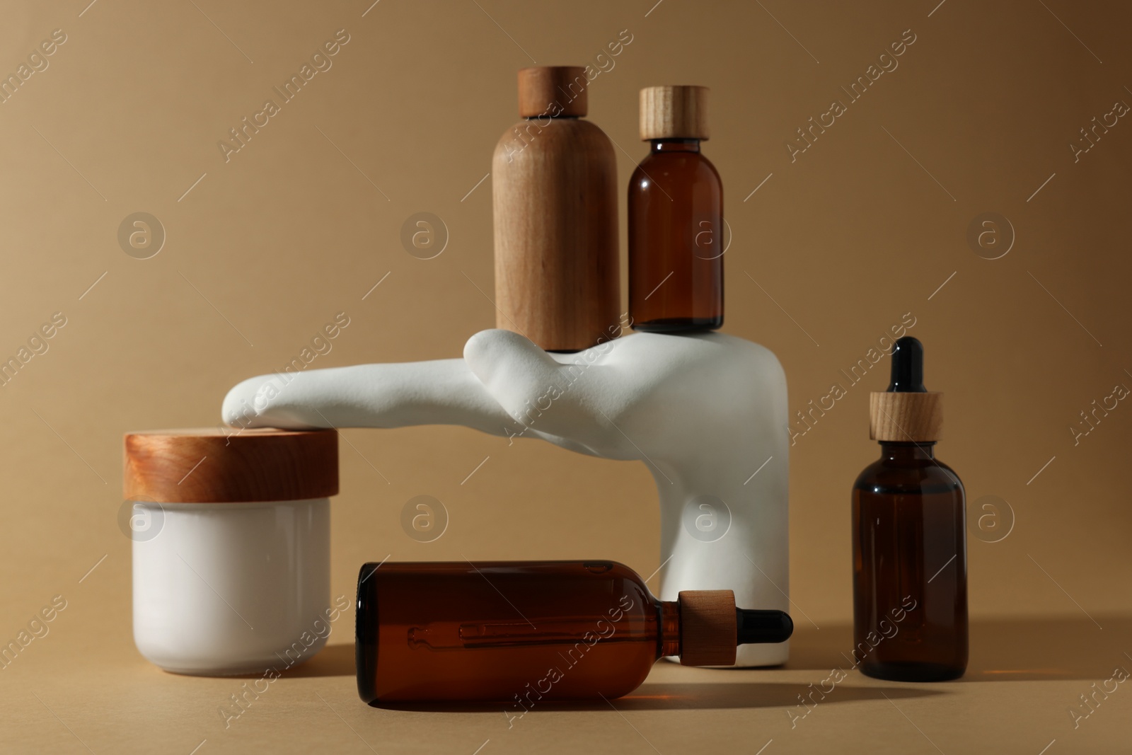 Photo of Bottles and jar of cosmetic products on dark beige background