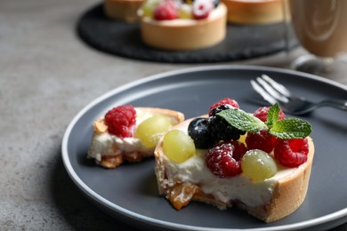 Photo of Delicious tartlet with berries on grey table, closeup