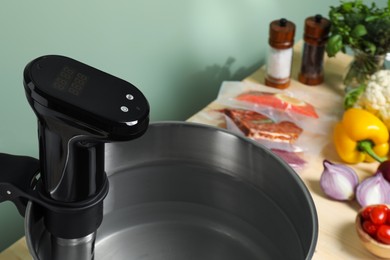 Photo of Sous vide cooker in pot and ingredients on table, closeup. Thermal immersion circulator