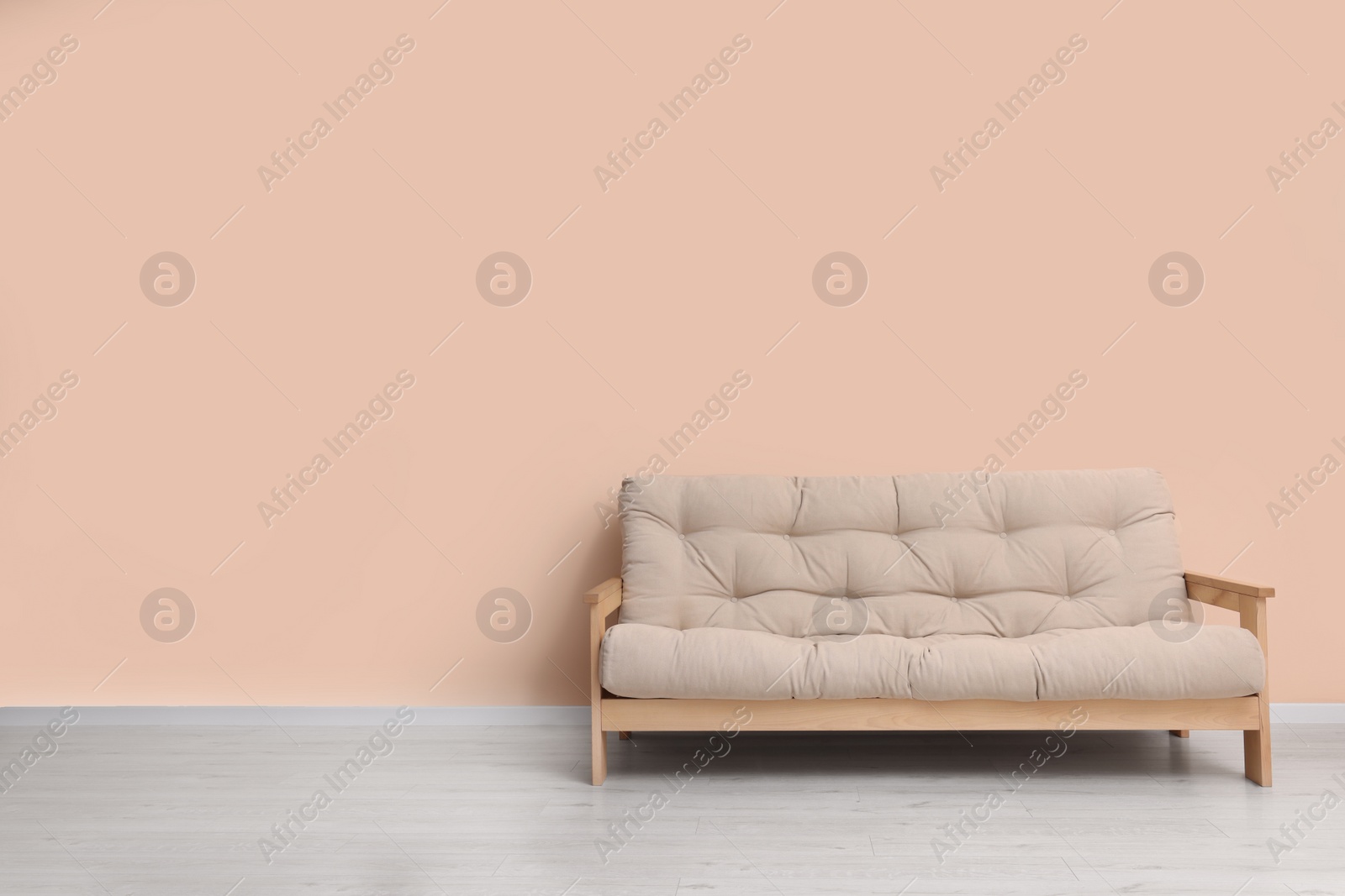 Photo of Comfortable sofa near beige wall indoors. Space for text