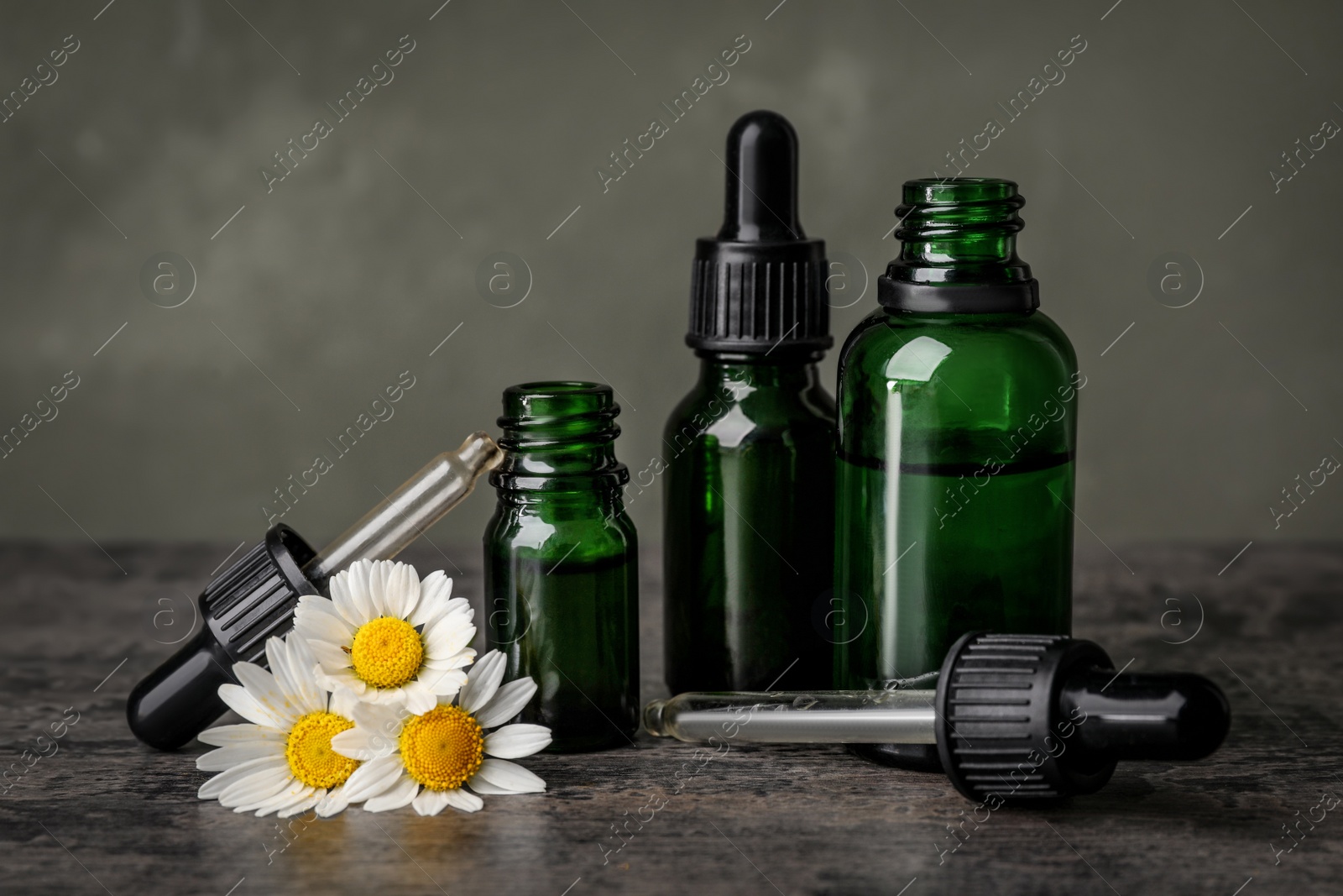 Photo of Composition with bottles of chamomile essential oil on table