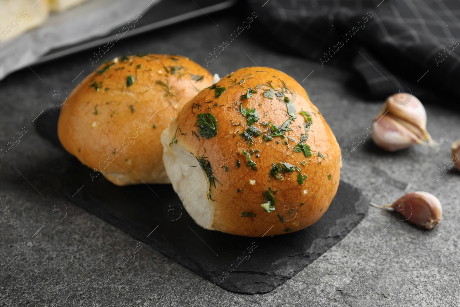 Photo of Traditional pampushka buns with garlic and herbs on grey table, closeup