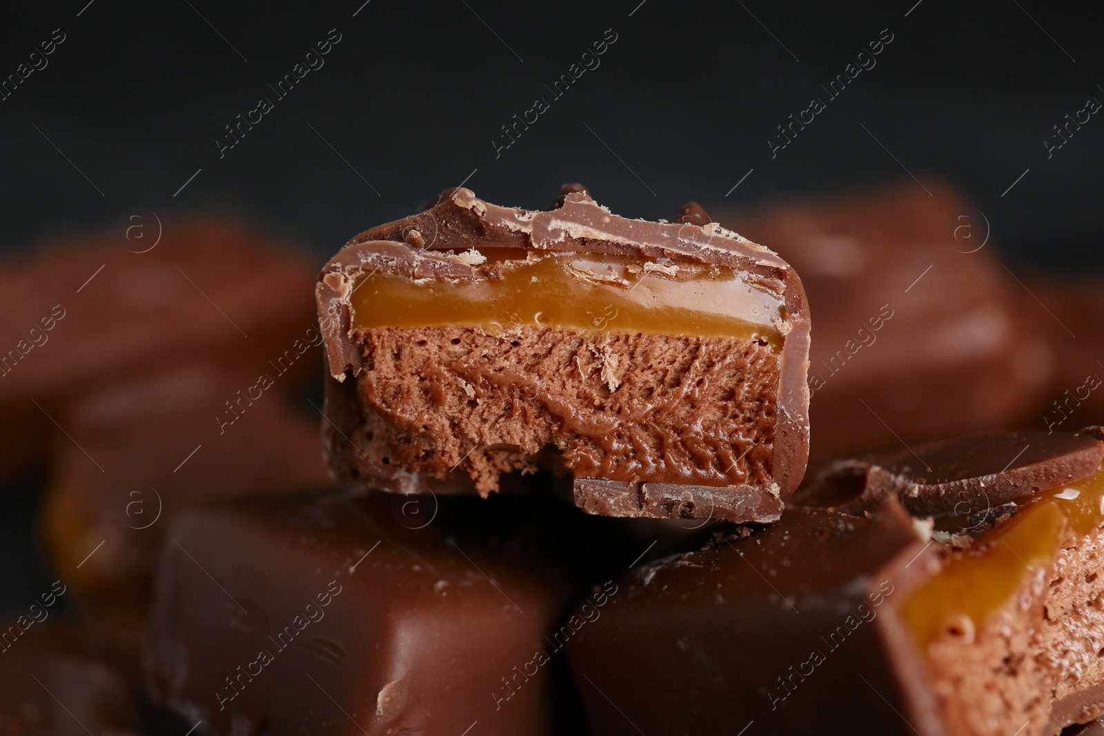 Photo of Delicious chocolate candy bars with caramel on dark background, closeup