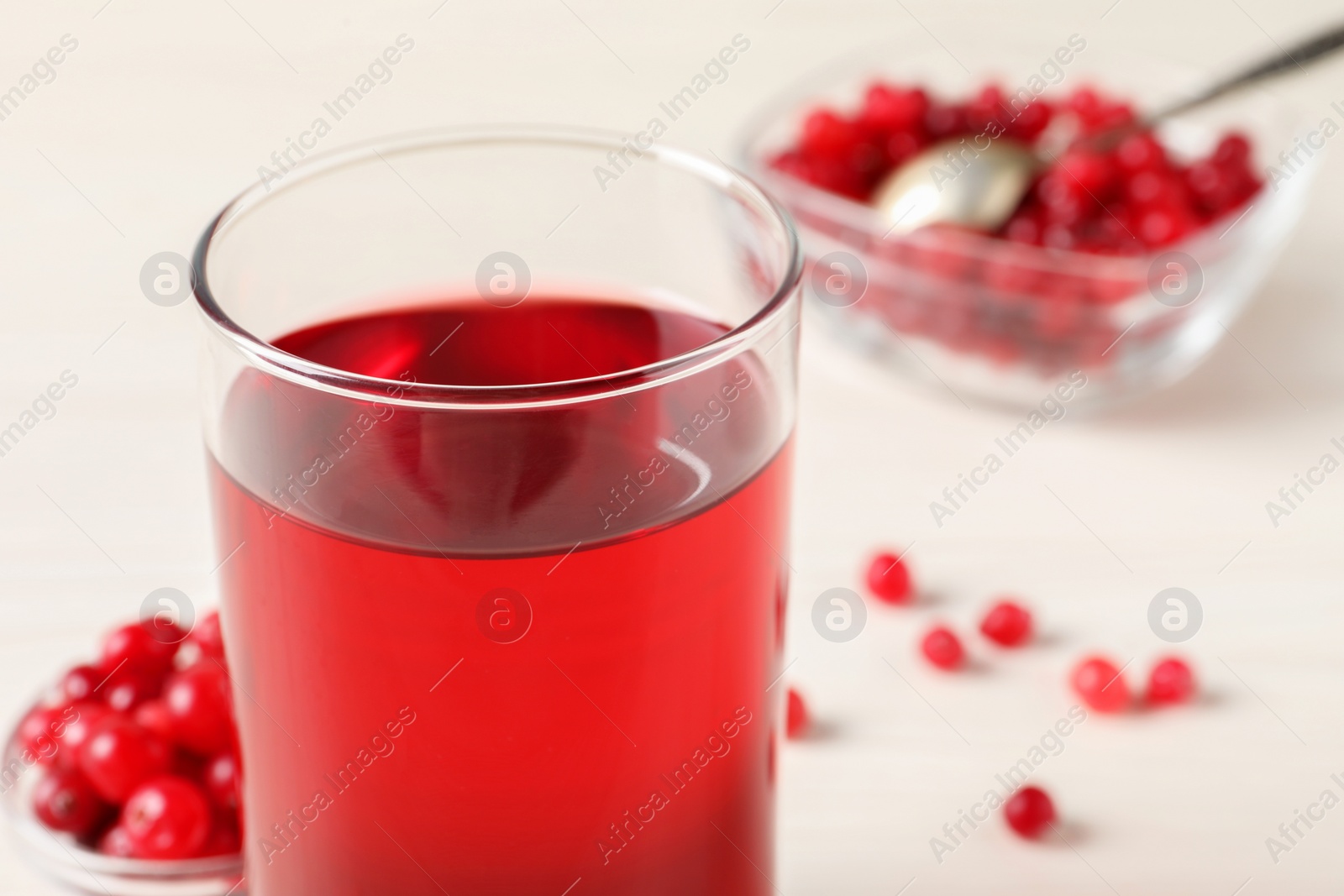 Photo of Tasty cranberry juice in glass and fresh berries on white wooden table, closeup