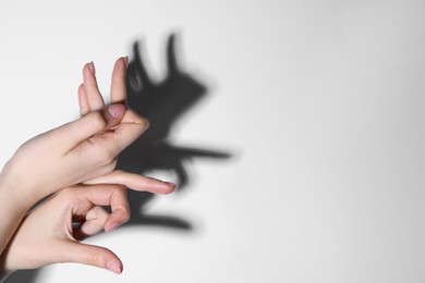 Shadow puppet. Woman making hand gesture like rabbit on light background, closeup. Space for text