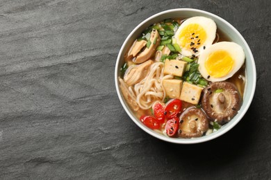 Photo of Noodle soup. Bowl of delicious ramen on black table, top view. Space for text