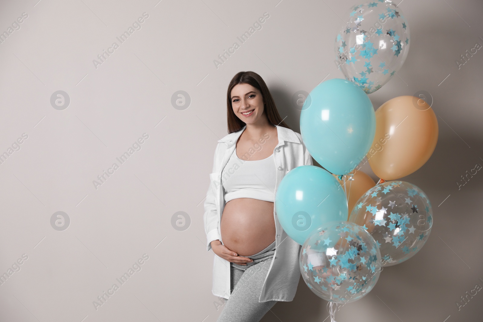 Photo of Happy pregnant woman with balloons near grey wall. Baby shower party