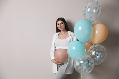 Photo of Happy pregnant woman with balloons near grey wall. Baby shower party