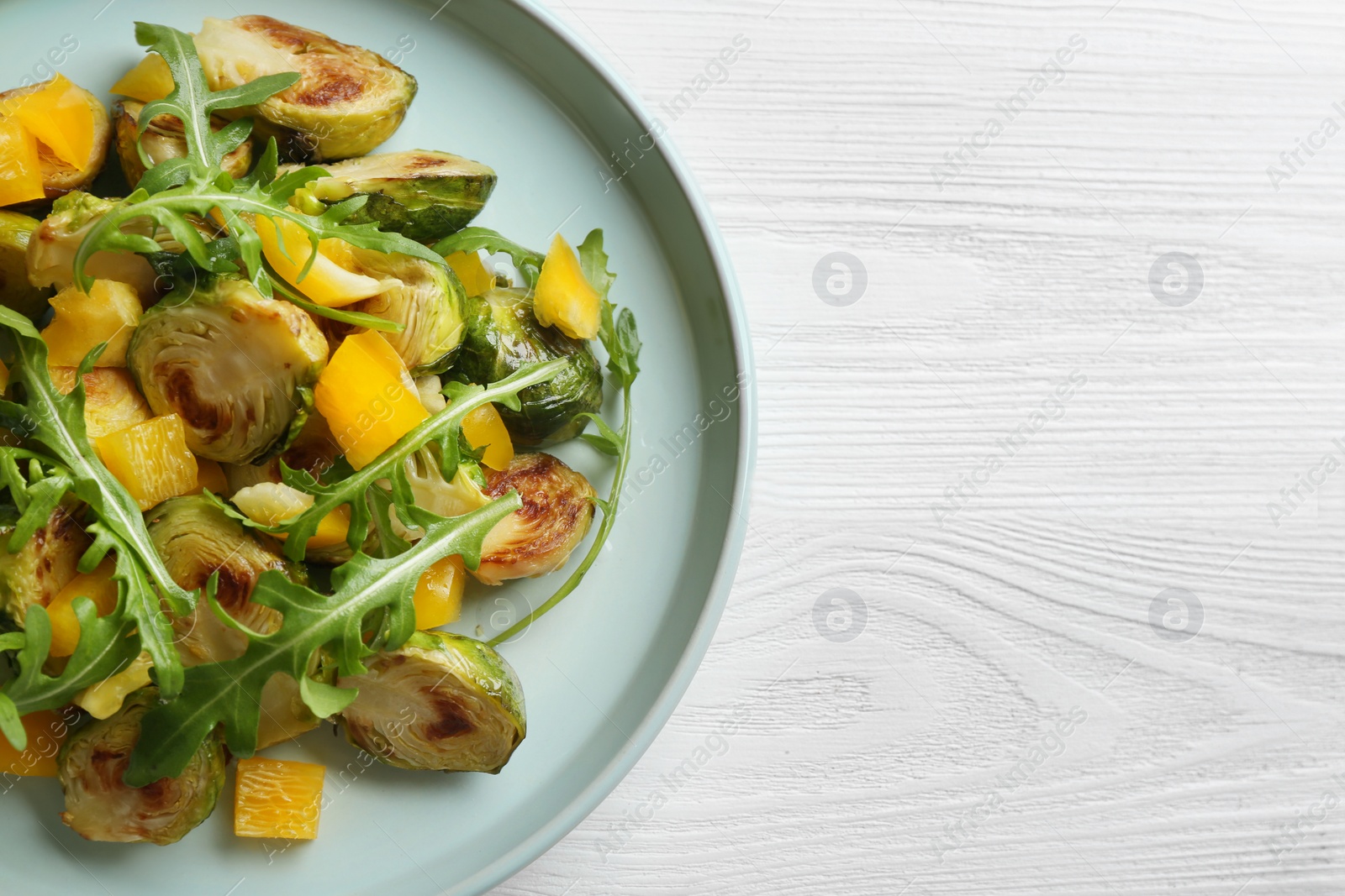 Photo of Delicious salad with roasted Brussels sprouts on white wooden table, top view. Space for text