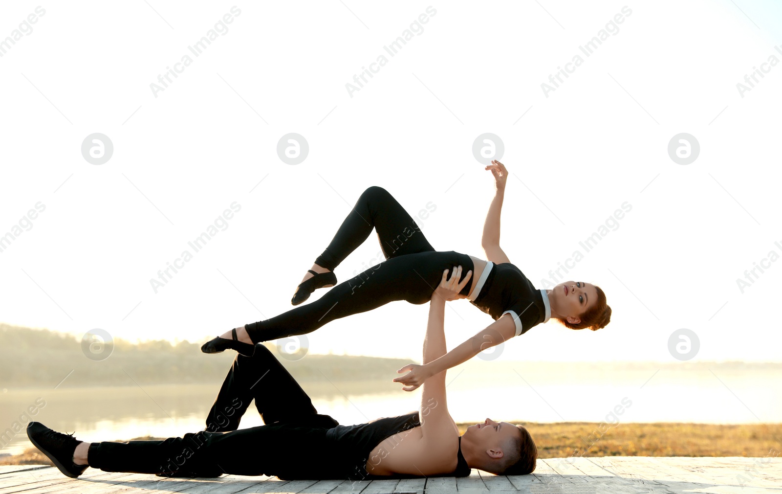 Photo of Beautiful young couple practicing dance moves near river at sunset