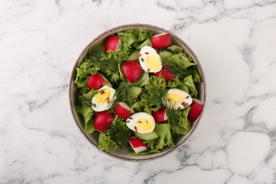 Delicious salad with radish, lettuce and boiled quail eggs on white marble table, top view