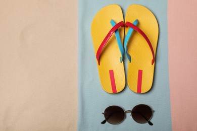 Photo of Beach towel, flip flops and sunglasses on sand, top view. Space for text