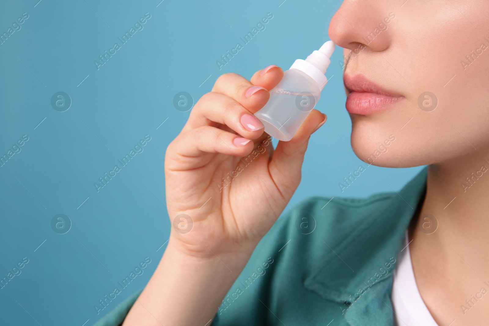 Photo of Woman using nasal spray on light blue background, closeup