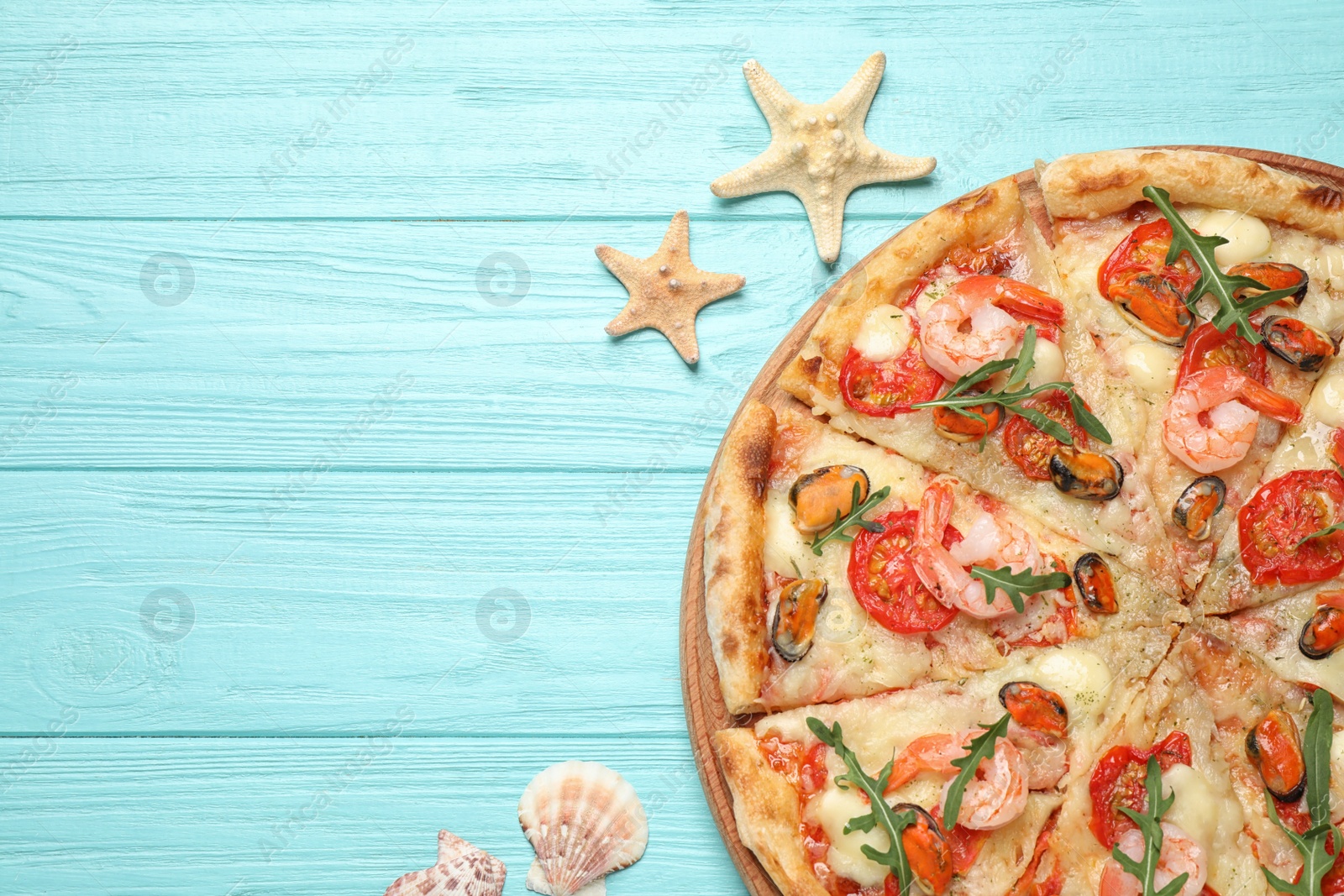 Photo of Delicious seafood pizza on light blue wooden table, flat lay. Space for text