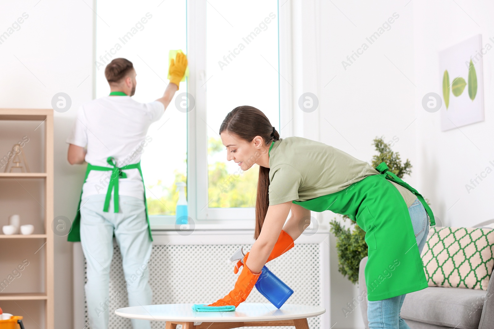 Photo of Team of professional janitors in uniform cleaning room