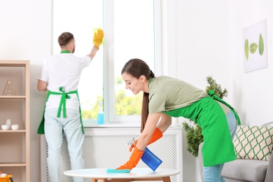 Team of professional janitors in uniform cleaning room