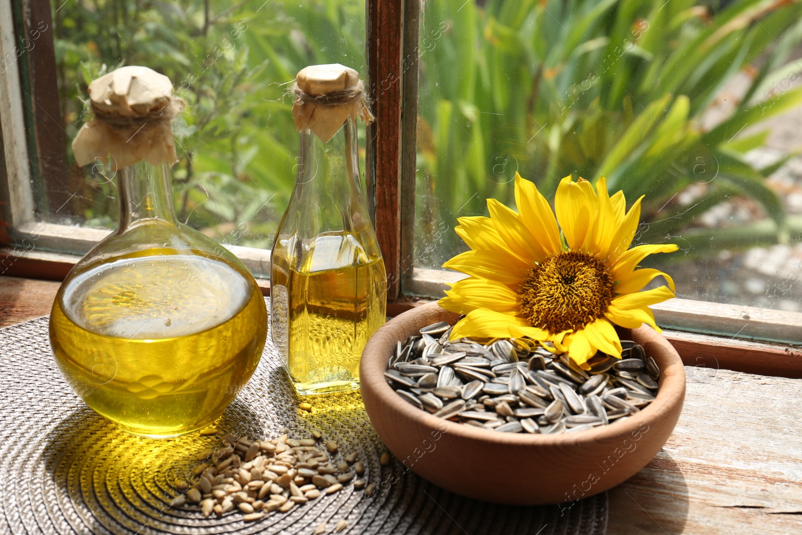 Photo of Bottles of sunflower oil, seeds and flower on wooden table indoors