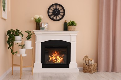 Photo of Stylish fireplace near potted plants and firewood in cosy living room