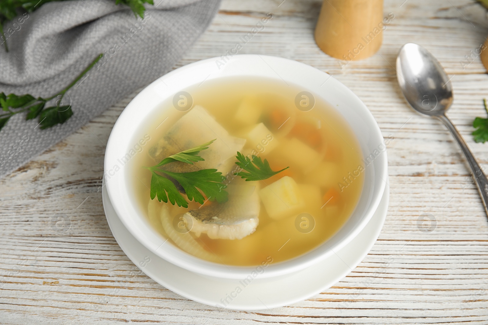 Photo of Delicious fish soup in bowl on white wooden table