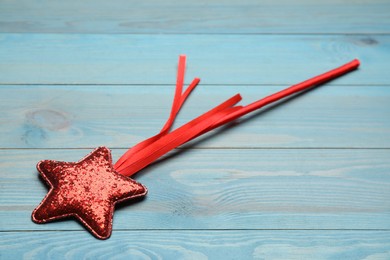 Photo of Beautiful red magic wand on turquoise wooden table