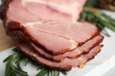 Photo of Cut delicious ham with rosemary on white table, closeup