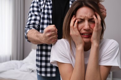 Photo of Man abusing scared woman in bedroom. Domestic violence