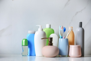 Roll-on deodorant and different toiletry on marble table near light wall