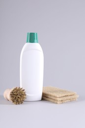 Bottle of cleaning product, brush and sponges on light background