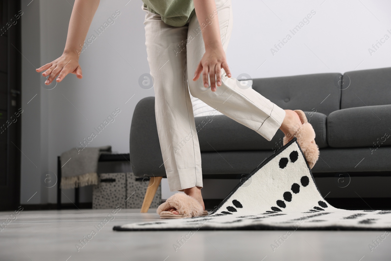 Photo of Woman tripping over carpet at home, closeup