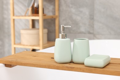 Photo of Set of bath accessories on tub in bathroom