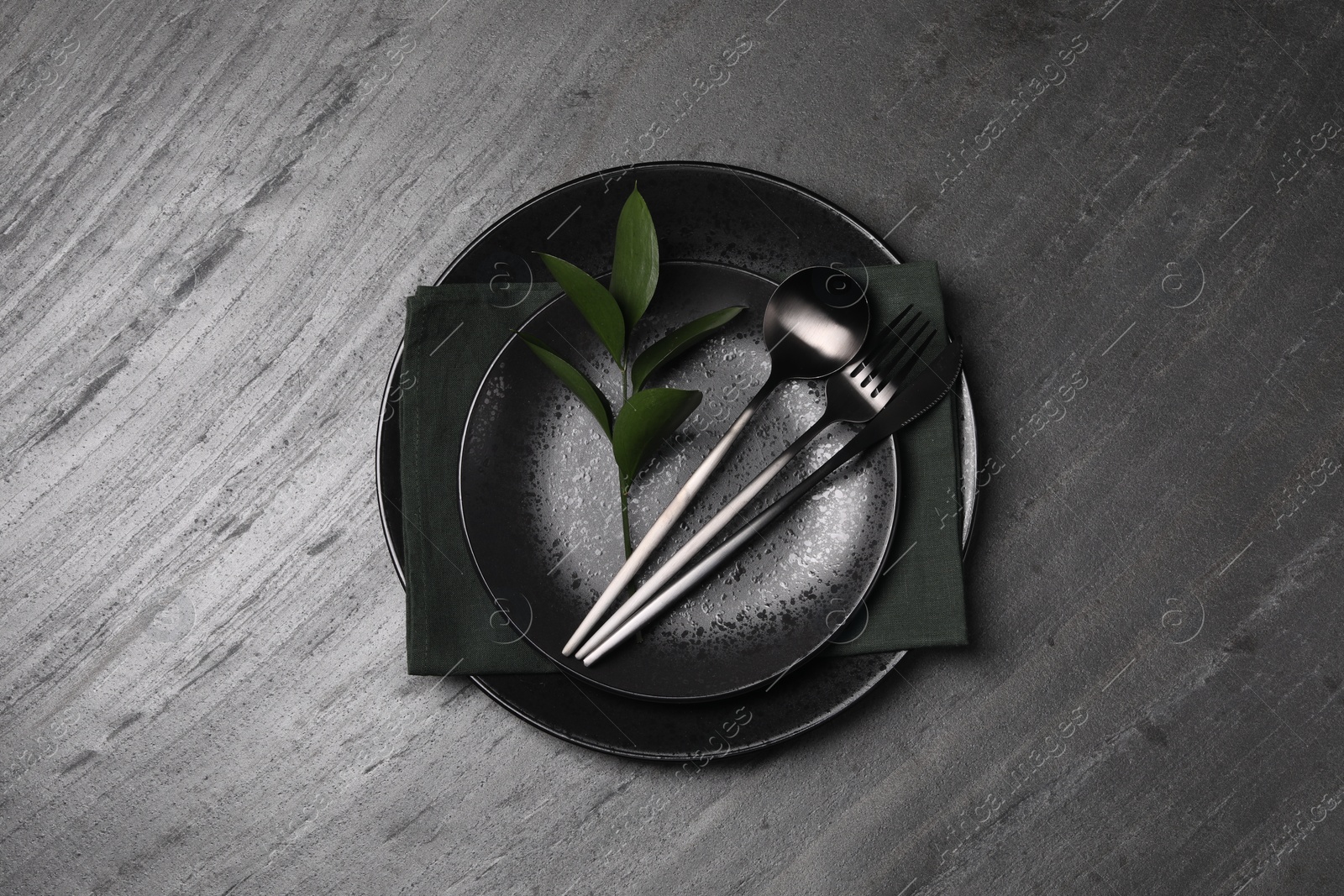 Photo of Elegant table setting. Plates, cutlery, napkin and branch with green leaves, flat lay