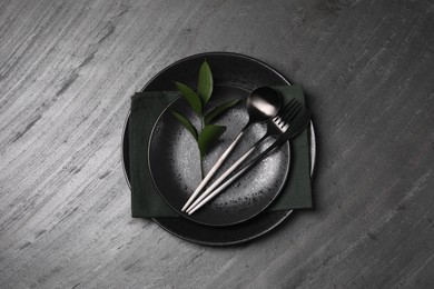Elegant table setting. Plates, cutlery, napkin and branch with green leaves, flat lay